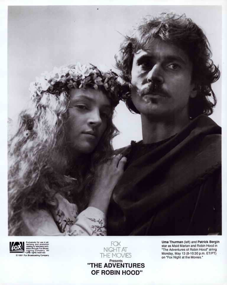 Black-and-white promotional photo of a man and a woman in medieval costumes, the woman wearing a flower crown, standing close together, with the title 'The Adventures of Robin Hood' at the bottom.