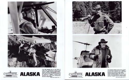 Promotional Alaska poster spread: left page shows a pilot in cockpit and a wrecked plane with a person among the crashes; right page shows a rugged man with a rifle and a bearded man in a heavy coat by a helicopter.