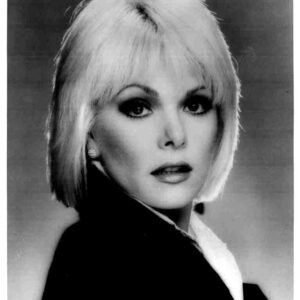 Black-and-white studio portrait of a woman with short blonde hair, looking at the camera.