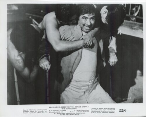 Black-and-white still of a man being restrained by two others in a scuffle, smiling as he is held back from a fight (film still from The Beachcomber).