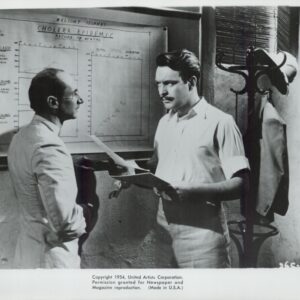 Two men in short-sleeve shirts study a wall chart titled 'Cholera Epidemic' while holding papers.