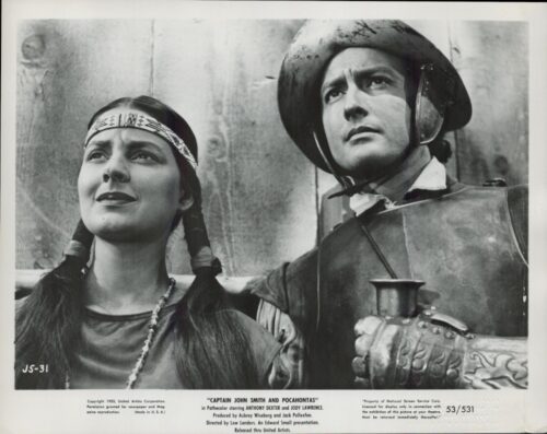 Black-and-white still of a Native American woman with braids and a man in armor, looking upward.