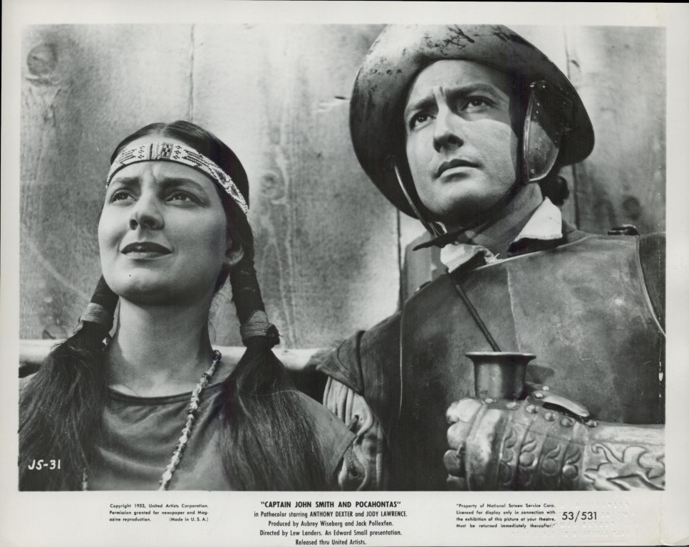 Black-and-white still of a Native American woman with braids and a man in armor, looking upward.