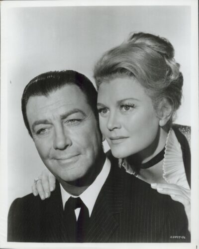Black-and-white studio portrait of a man in a suit and a woman beside him, her hand resting on his shoulder.