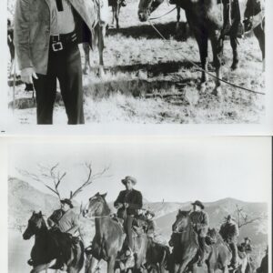 Black-and-white photo of cowboys on horseback; a man in front waves toward the camera while others ride in the background in a prairie setting.