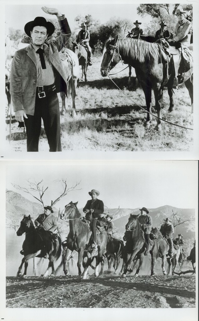 Black-and-white photo of cowboys on horseback; a man in front waves toward the camera while others ride in the background in a prairie setting.