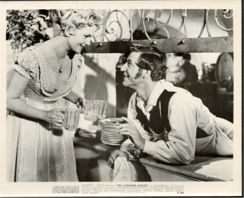 Vintage scene: woman in dress serves drinks to a man at a bar counter, smiling.