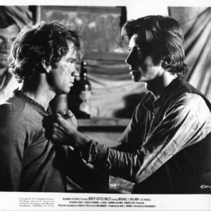 Black-and-white still of two men in a tense confrontation; one man grips the other by the shirt collar.