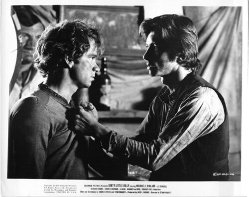 Black-and-white still of two men in a tense confrontation; one man grips the other by the shirt collar.