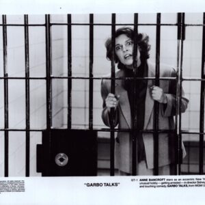 Still from Garbo Talks showing a distressed woman behind jail bars, gripping the bars with a wide-eyed expression.