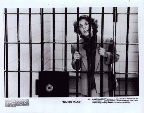 Still from Garbo Talks showing a distressed woman behind jail bars, gripping the bars with a wide-eyed expression.