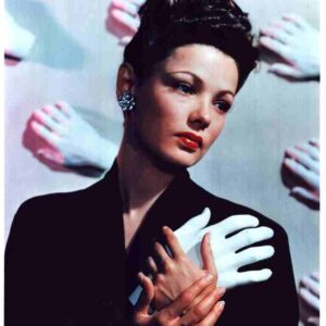 Portrait of a woman in a black coat with short dark hair, looking to the left, surrounded by pale gloved hands in the backdrop.