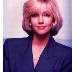 Professional head-and-shoulders portrait of a woman with pink hair wearing a dark blazer, facing the camera.