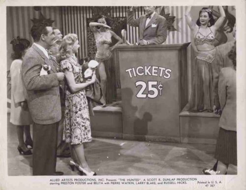 Black-and-white game-show scene with a host at a ticket booth reading 'Tickets 25¢'; a woman in a floral dress holds a child, while a man and other guests stand nearby as showgirls pose on stage in the background.
