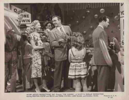 Black-and-white promotional photo from a 1950s film set showing guests in party attire chatting among balloons in the background.
