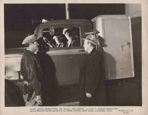 Black-and-white promotional still from the film The Hunted, showing two men in hats talking to two people inside a large truck at night.