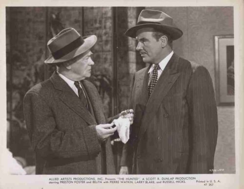 Two men in 1940s suits and fedoras stand facing each other as one offers a white handkerchief or cloth to the other.