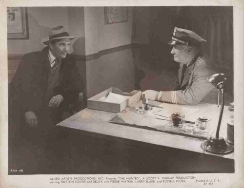 A man in a fedora sits at a desk across from a uniformed officer, as if being questioned in a police station.