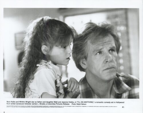 Black-and-white film still of a man and a young girl closely watching something off-camera, conveying a thoughtful moment between father and daughter in a family scene from I'll Do Anything.