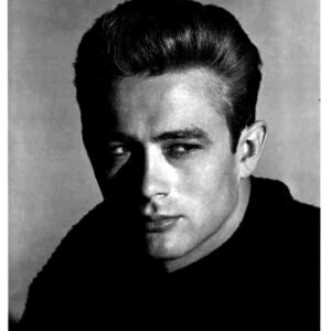 Black-and-white head-and-shoulders portrait of a man with slicked-back hair, looking toward the camera with dramatic lighting.