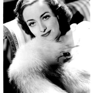 Vintage black-and-white portrait of a woman with a fur stole looking at the camera.