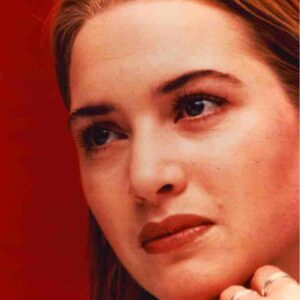 Close-up portrait of a woman with light skin and light brown hair against a solid red background, looking to the side.