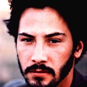 Close-up portrait of a man with dark hair and a beard, looking intently at the camera.