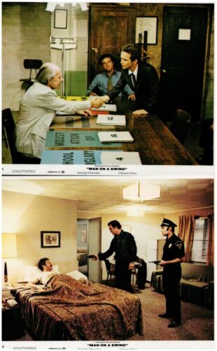 Two men shake hands across a desk in a film set/office; production folders and paperwork are on the table behind them.