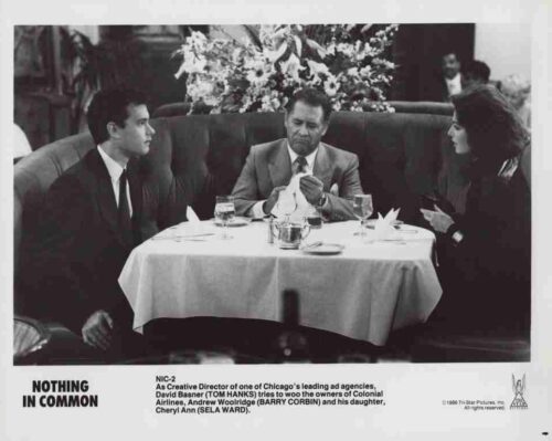 Black-and-white promotional photo of three people in formal attire seated around a round table in a restaurant; the caption reads 'NOTHING IN COMMON' at the bottom.