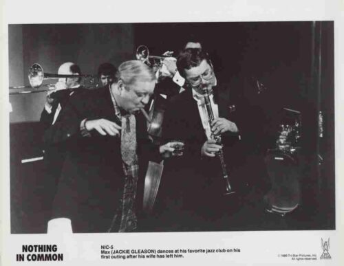 Black-and-white photo of a jazz band performing in a club; a man gestures with a drink while another plays a clarinet, with a trombone and bass visible in the background. Caption reads 'NOTHING IN COMMON'.