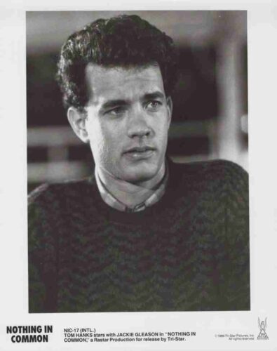 Black-and-white portrait of Tom Hanks from the movie Nothing in Common, shown from the chest up in a dark knit sweater, looking to the side.