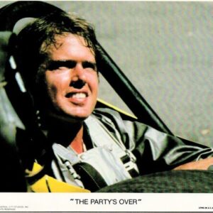 Pilot in a cockpit wearing a gray flight suit and headset, smiling; caption at bottom reads 'THE PARTY'S OVER'