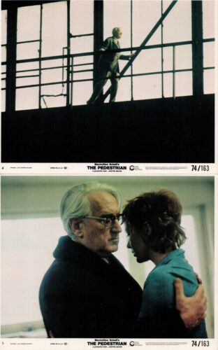 Man in a suit climbs a metal staircase along a dark industrial interior, silhouetted against large windows.