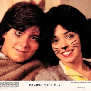 Two young people smile with their heads close together; one has cat whiskers drawn on her face in a movie poster for 'Promises in the Dark'.