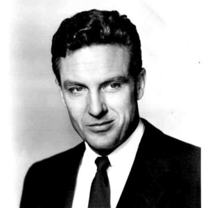 Black-and-white head-and-shoulders portrait of a man in a dark suit and tie.