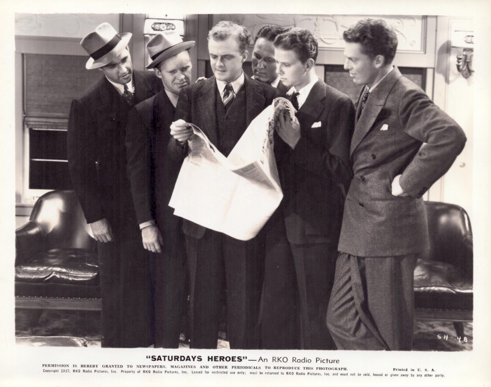 Six men in 1930s suits gather around a large newspaper, reading it together in a studio-like room.
