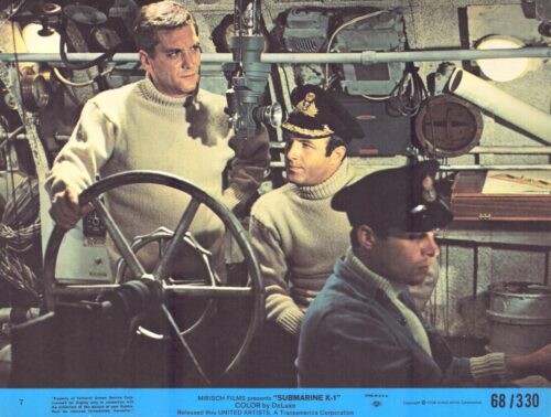 Three sailors in a submarine control room around a large wheel, focused on their tasks in knit sweaters and caps.