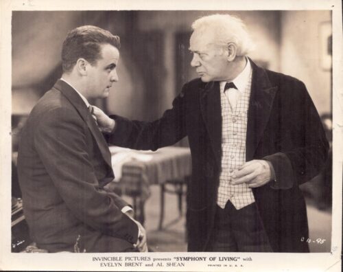 Older man with white hair consoles a younger man in a suit; film promo image for Symphony of Living.