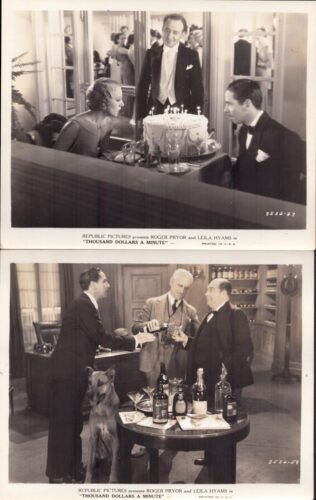 Couple in formal wear sit at a table with a large birthday cake, as a man in a suit stands nearby in a party setting.
