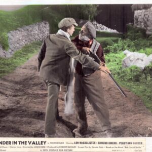 Two men in vintage clothing wrestle over a shotgun on a rural dirt road, with stone walls and greenery in the background.