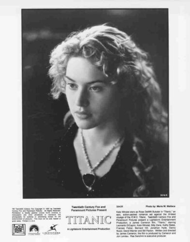 Black-and-white promotional portrait from Titanic showing a young woman with wavy hair and a heart-shaped pendant necklace.