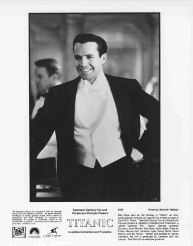 Black-and-white photo of a smiling man in a tuxedo, arms on hips, as part of a Titanic film poster.