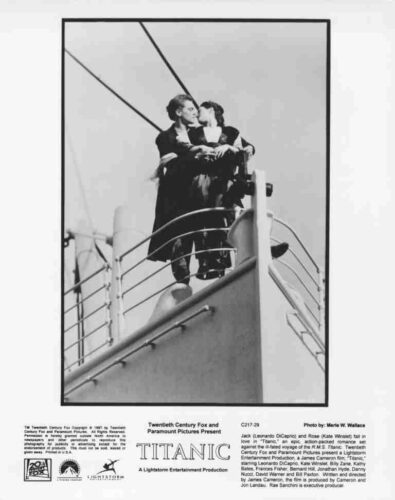 Black-and-white Titanic movie poster: a couple kissing at the bow of a ship, with railings and sails visible in the background, front-center.