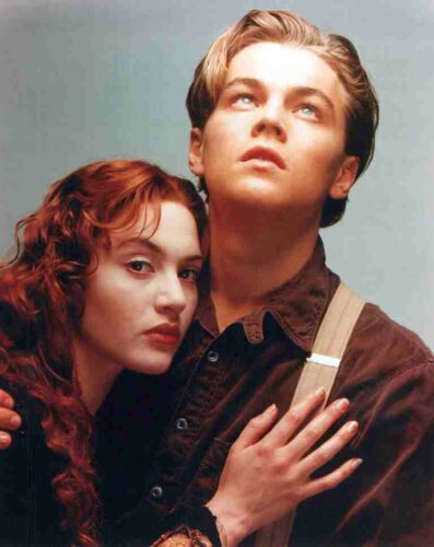 Romantic vintage portrait of a young couple embracing, the woman resting against the man's chest with a hopeful gaze upward.