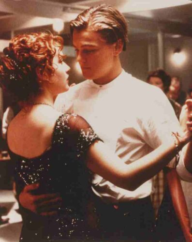 Couple dancing closely at a formal event; woman in a sequined black dress, man in a white shirt.