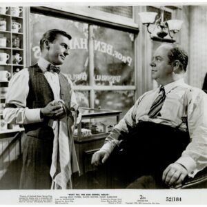 Production still from 'Wait Till the Sun Shines, Nellie': a young man in a vest and bow tie talks with a seated man in suspenders inside a shop.