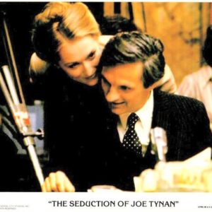 Man in a dark suit and a woman leaning in close over his shoulder, smiling, from the poster for The Seduction of Joe Tynan.