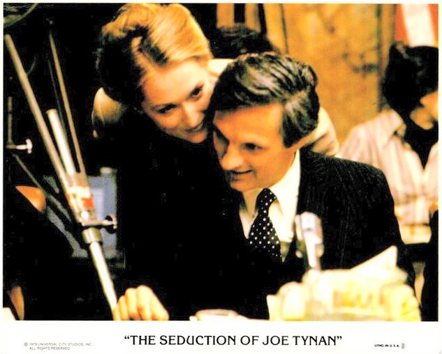 Man in a dark suit and a woman leaning in close over his shoulder, smiling, from the poster for The Seduction of Joe Tynan.