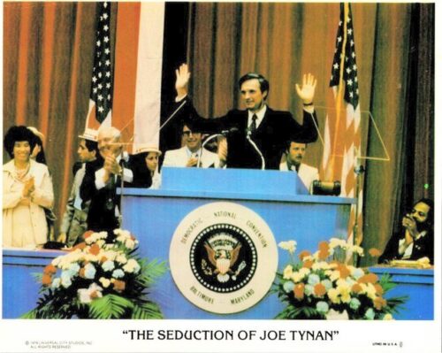 Film poster for The Seduction of Joe Tynan: a man at a podium with arms raised, flanked by US flags and a presidential seal behind him.