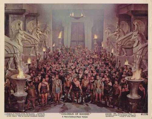 Movie poster for Colossus of Rhodes: a large crowd of armored warriors in a torch-lit temple, flanked by colossal winged-horse statues.